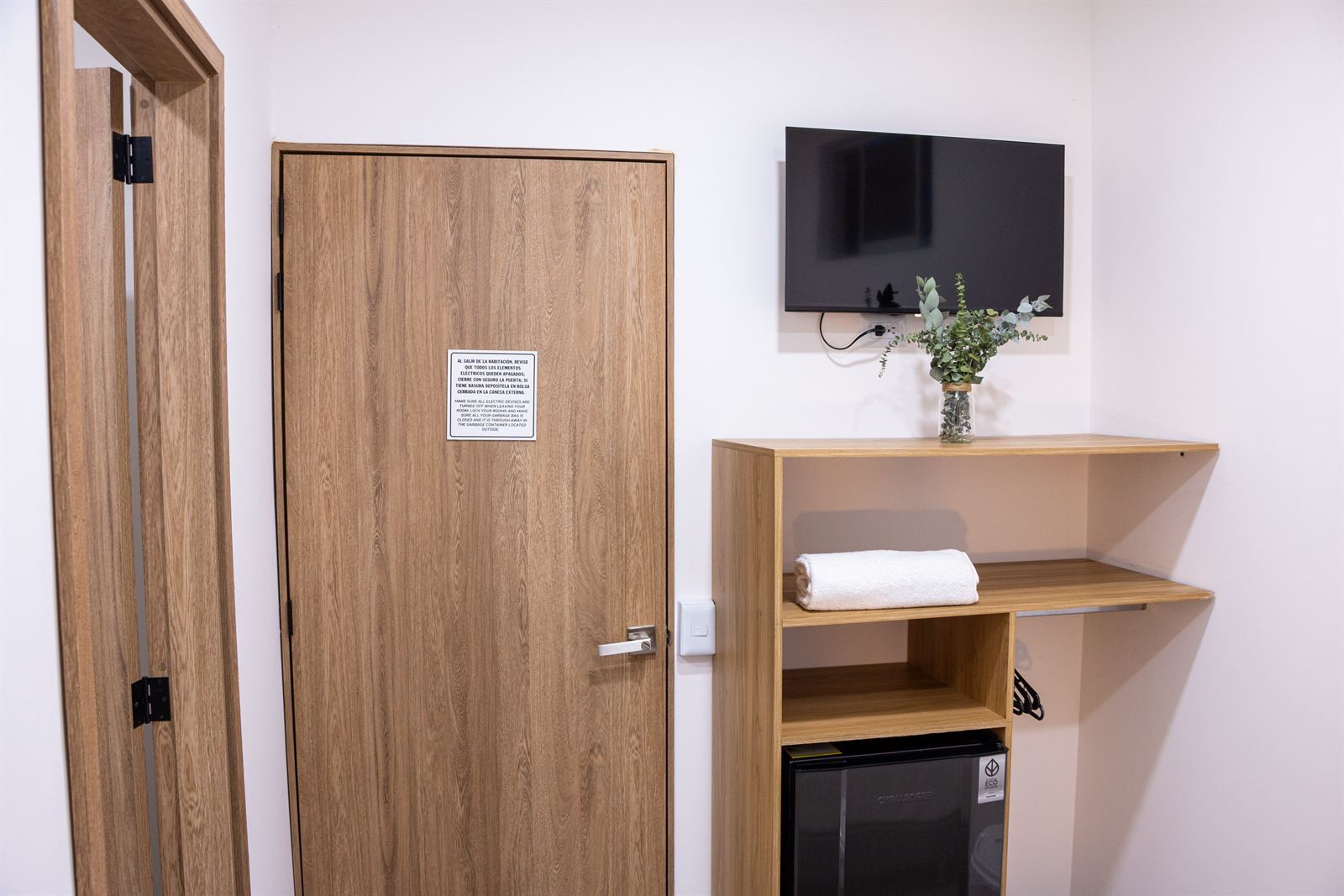 Puerta de madera de la habitación, smart TV en la pared y estante con toallas y mini nevera — Doble Superior Internas