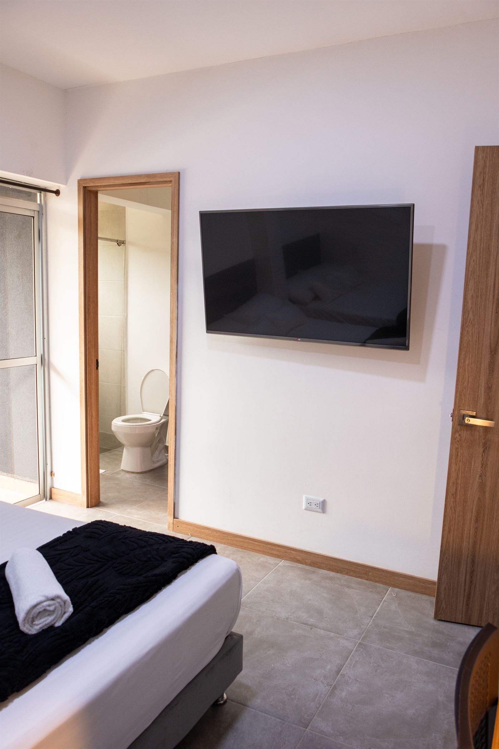 Smart TV murale à côté de la salle de bain privée avec porte en bois — Cuádruple Superior Twin