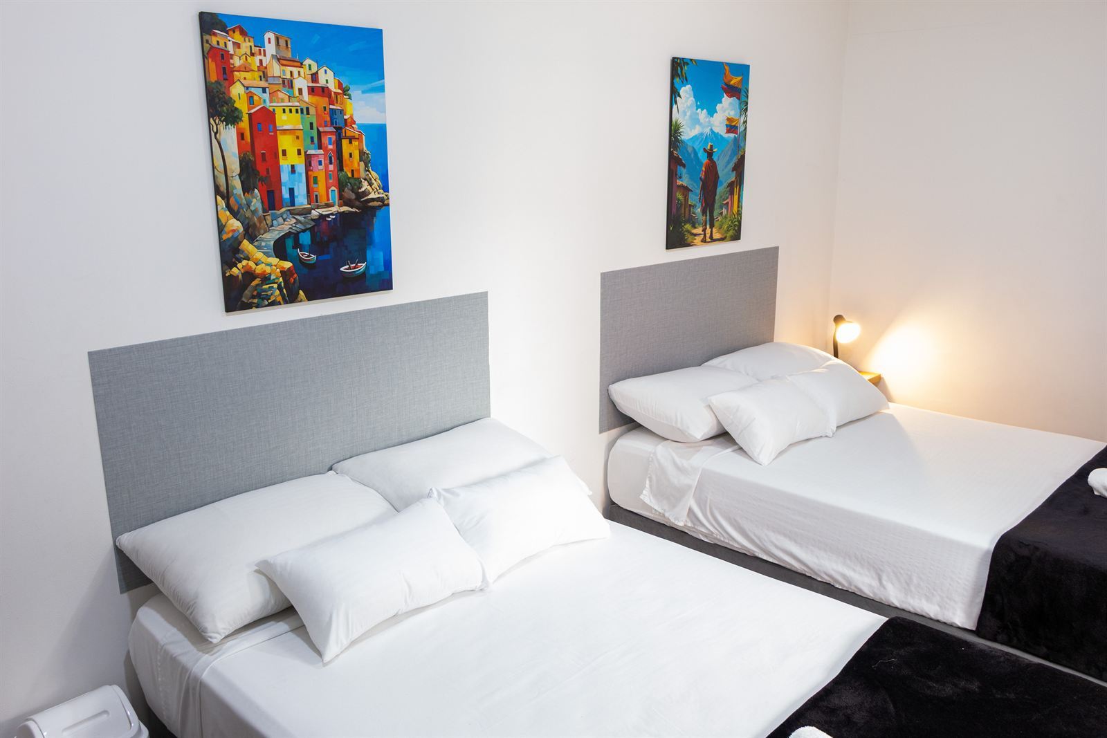 Deux lits simples avec têtes de lit grises et tableaux décoratifs colorés — Cuádruple Superior Twin
